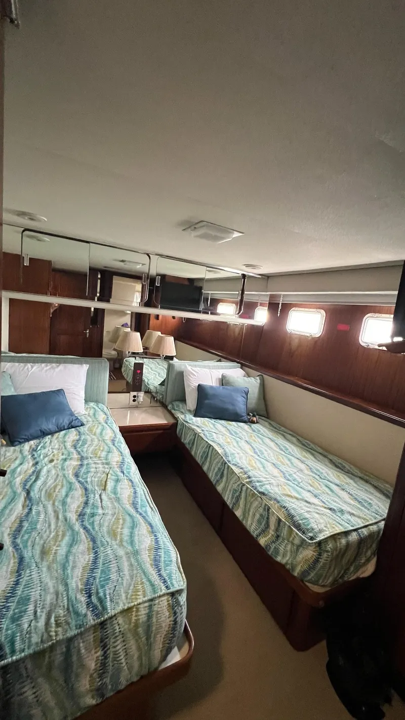 Slide: The Image of 1987 Hatteras Motoryacht cabin with twin beds, patterned bedding, and wooden interior. - 41