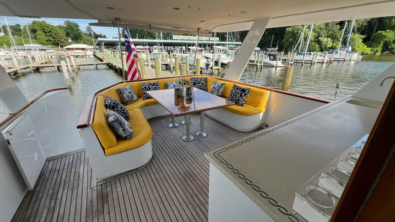 Slide: The Image of 1987 Hatteras Motoryacht deck with yellow seating, table, and marina view. - 44