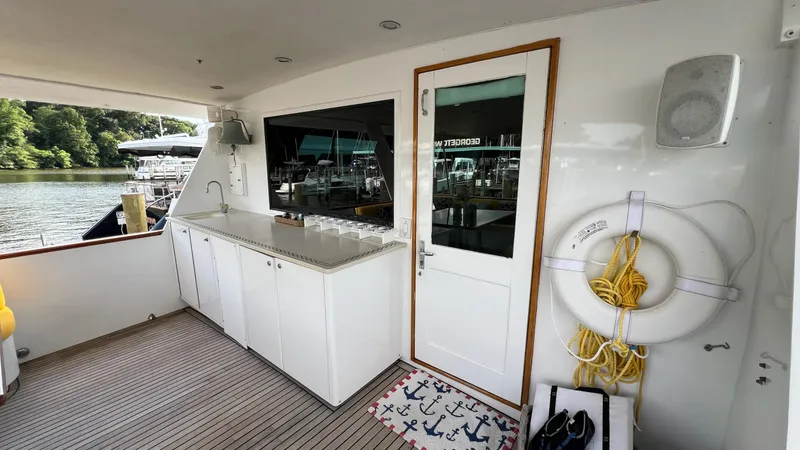 Slide: The Image of 1987 Hatteras Motoryacht deck with cabinets, door, and life preserver by the water. - 45