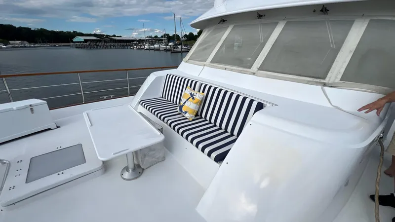 Slide: The Image of 1987 Hatteras Motoryacht deck with striped seating and table, overlooking marina. - 46