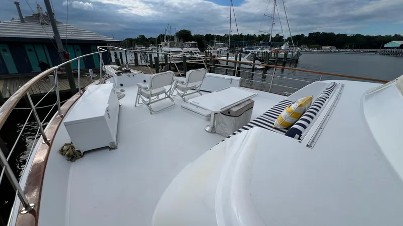 Slide: The Image of 1987 Hatteras Motoryacht deck with chairs and striped cushions, docked at a marina. - 47