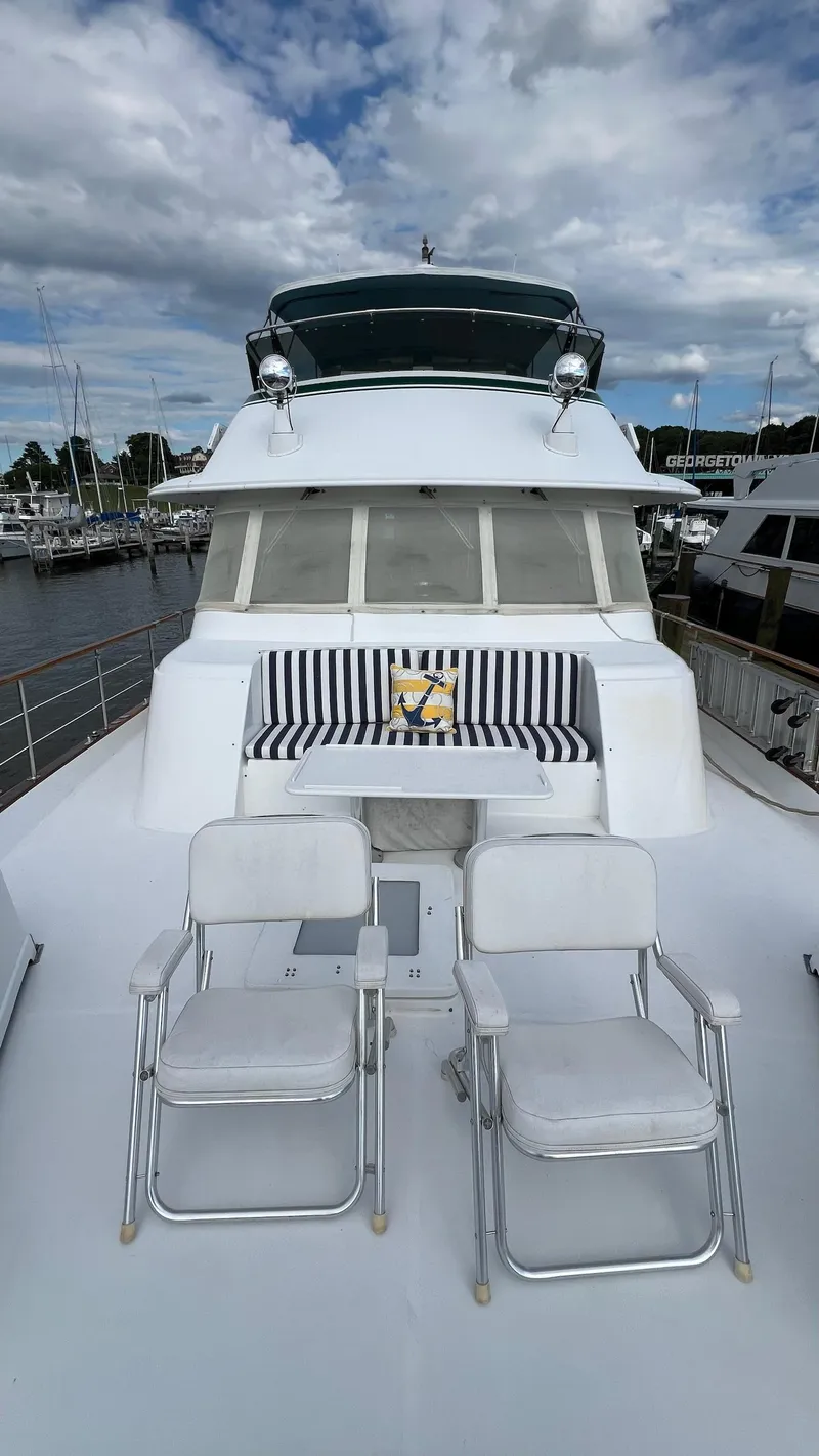 Slide: The Image of 1987 Hatteras Motoryacht with striped seating and chairs on deck, docked at marina. - 48