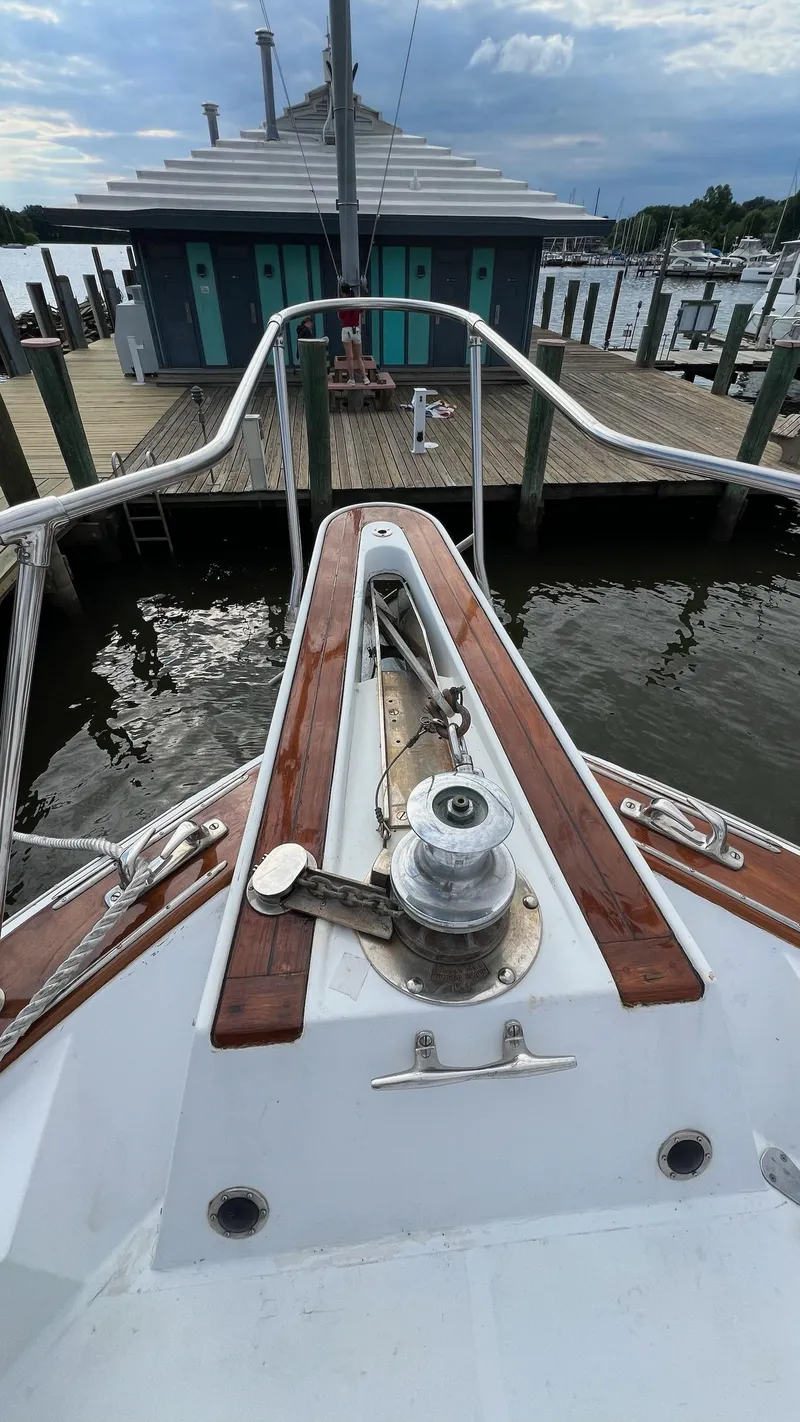 Slide: The Image of 1987 Hatteras Motoryacht bow view at dock, featuring wooden deck and winch. - 49