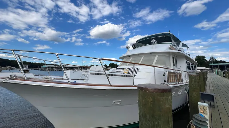 Slide: The Image of 1987 Hatteras Motoryacht docked under a vibrant blue sky with scattered clouds. - 5