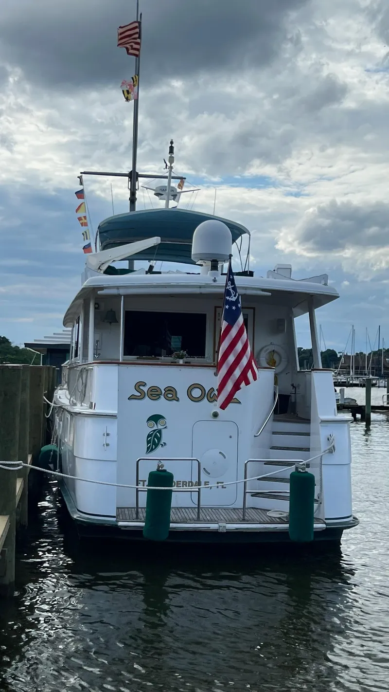 Slide: The Image of 1987 Hatteras Motoryacht docked, displaying flags and American flag, under cloudy sky. - 7