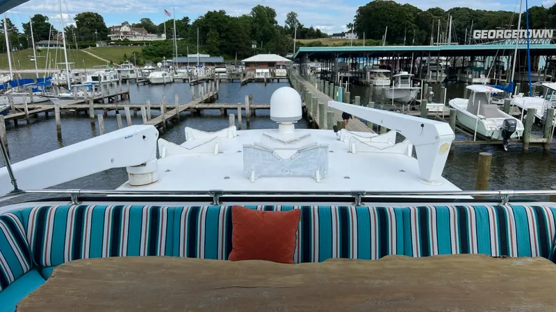 Slide: The Image of 1987 Hatteras Motoryacht docked at marina, featuring striped seating and wooden table. - 8