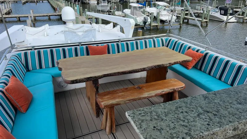 Slide: The Image of 1987 Hatteras Motoryacht deck with rustic wooden table, striped seating, and marina view. - 9