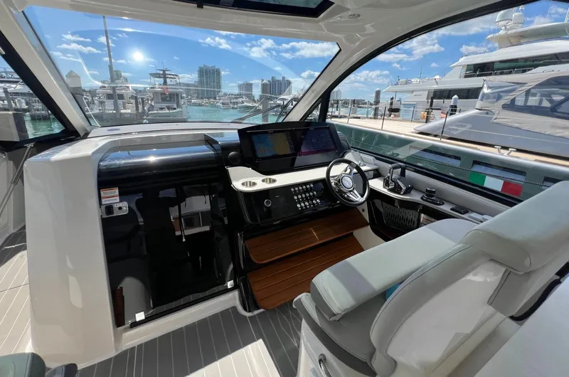 Slide: The Image of 2023 Sea Ray Sundancer 370 OB helm with modern controls and marina view. - 14