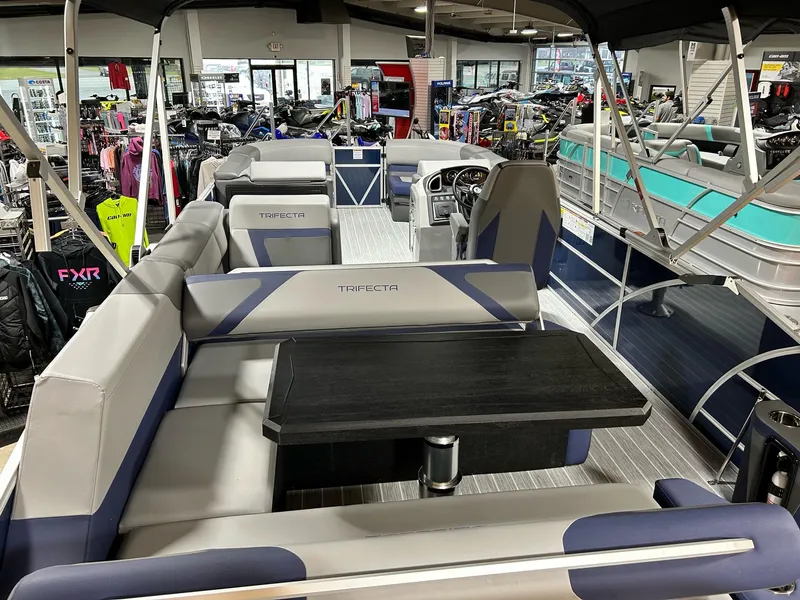 Slide: The Image of 2024 Trifecta 23SBESS pontoon boat interior with seating and table in showroom. - 8