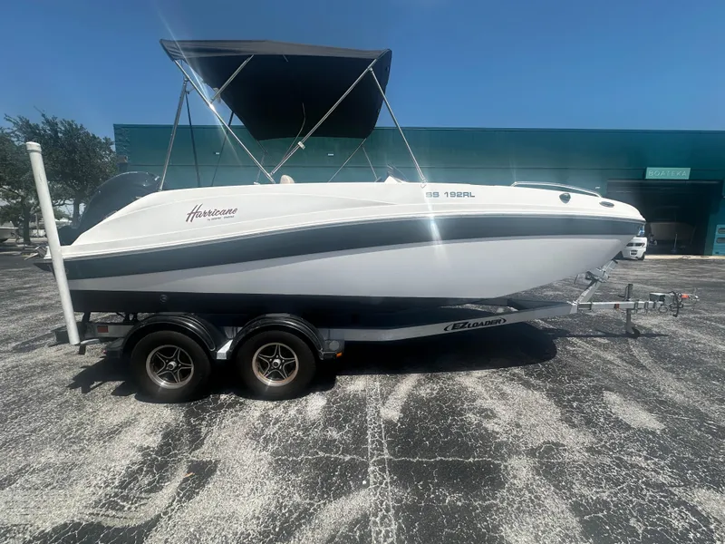 The Image of 2021 Hurricane SunDeck Sport 192 RL OB boat on trailer, parked outdoors under clear sky. - 0