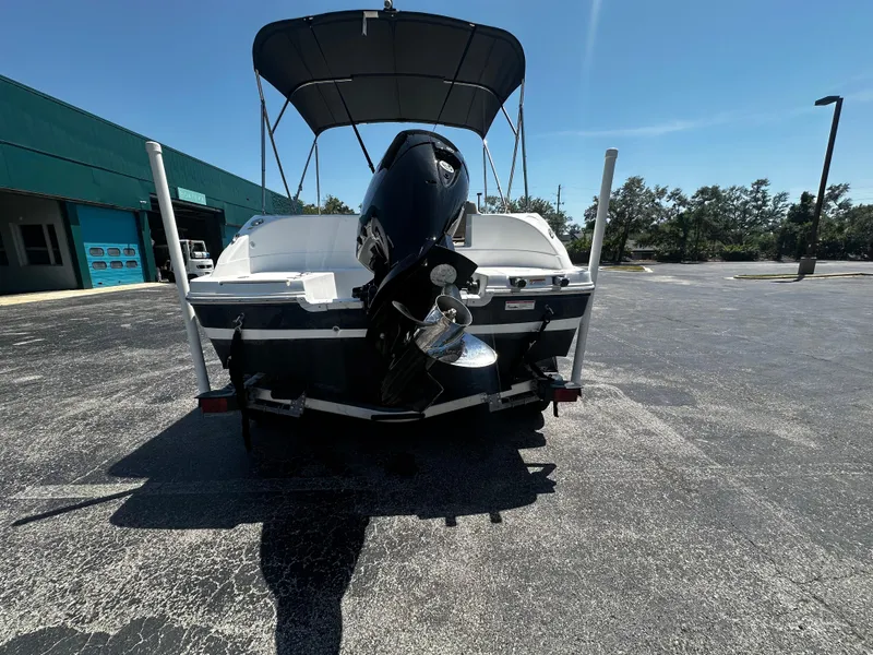Slide: The Image of 2021 Hurricane SunDeck Sport 192 RL OB boat, rear view with outboard motor, parked outdoors. - 2