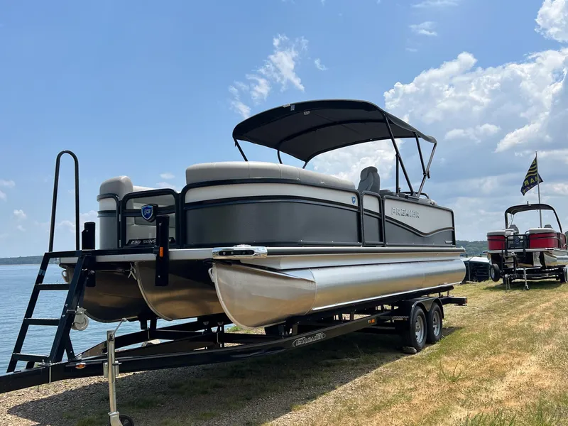 Slide: The Image of 2024 Premier 230 Sunsation RE pontoon boat on trailer by the lake. - 1