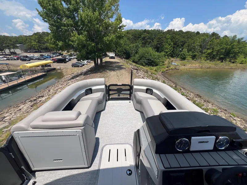 Slide: The Image of 2024 Premier 230 Sunsation RE pontoon boat interior, docked by a scenic lake. - 12