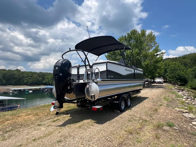 Slide: The Image of 2024 Premier 230 Sunsation RE pontoon boat on a trailer by a lake. - 3