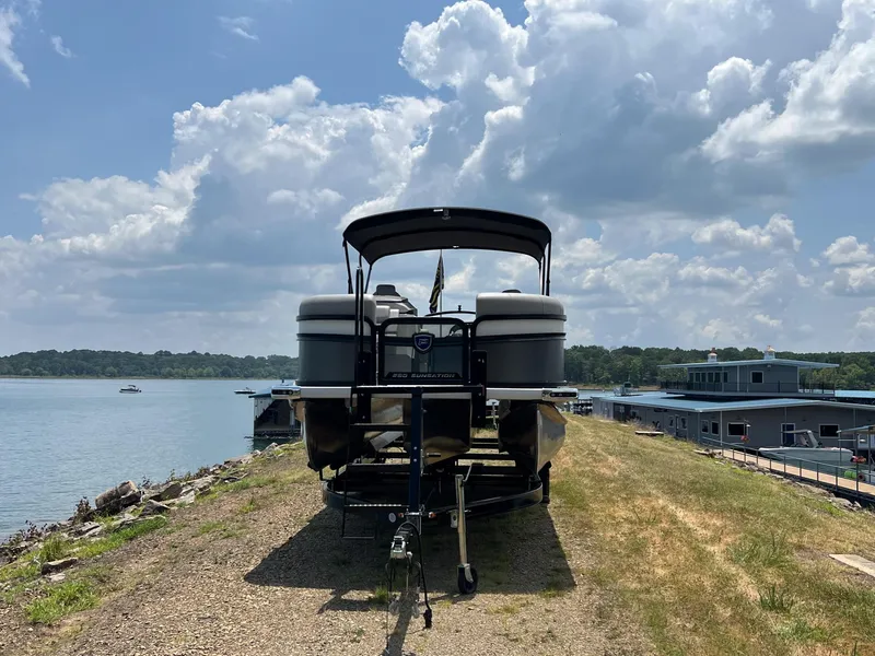 Slide: The Image of 2024 Premier 230 Sunsation RE pontoon boat on a trailer by a lake. - 4