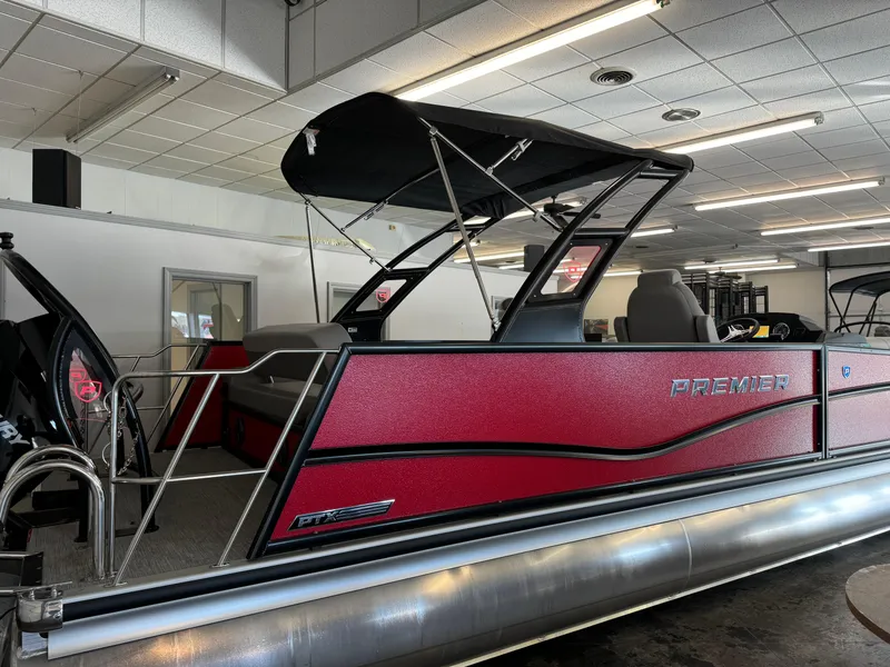 Slide: The Image of 2024 Premier 250 SunSation RL pontoon boat in showroom, featuring sleek red design. - 2
