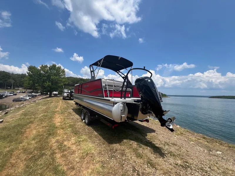 Slide: The Image of 2024 Premier 250 SunSation RF pontoon boat on a trailer by a lake. - 5