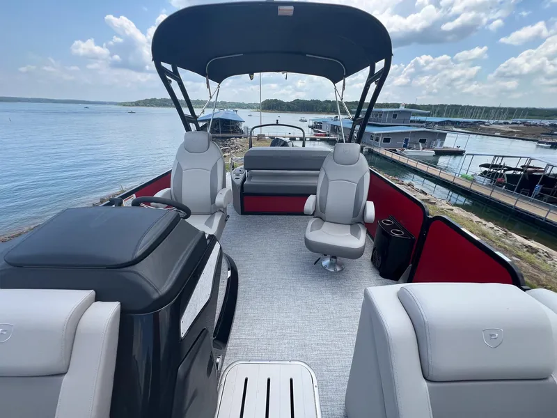 Slide: The Image of 2024 Premier 250 SunSation RF pontoon boat interior with seating and canopy on a lake. - 6