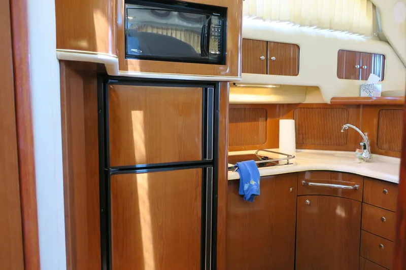 Slide: The Image of 2002 Sea Ray 400 Sedan Bridge yacht kitchen with wood cabinetry, fridge, microwave, and sink. - 40
