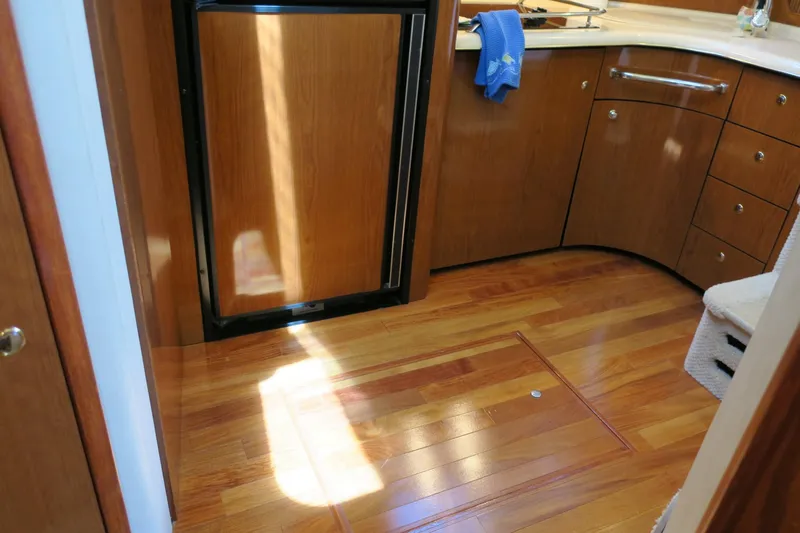 Slide: The Image of 2002 Sea Ray 400 Sedan Bridge kitchen with wooden cabinets and flooring. - 41