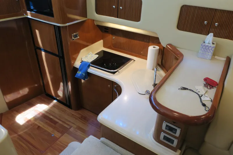 Slide: The Image of 2002 Sea Ray 400 Sedan Bridge kitchen area with stove, sink, and wooden cabinetry. - 44