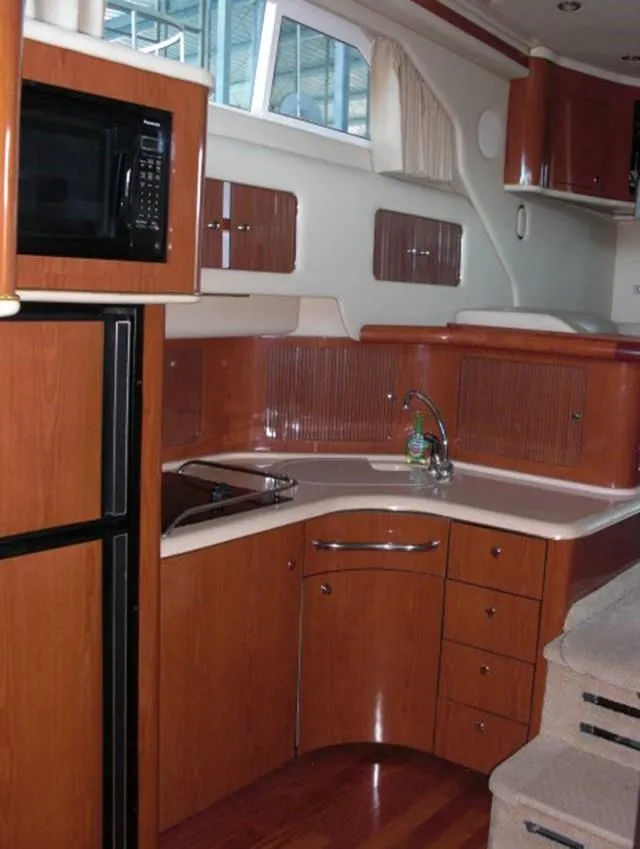 Slide: The Image of 2002 Sea Ray 400 Sedan Bridge kitchen with microwave, sink, and wooden cabinetry. - 5