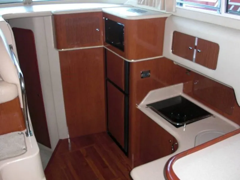 Slide: The Image of 2002 Sea Ray 400 Sedan Bridge kitchen area with wood cabinetry and appliances. - 6