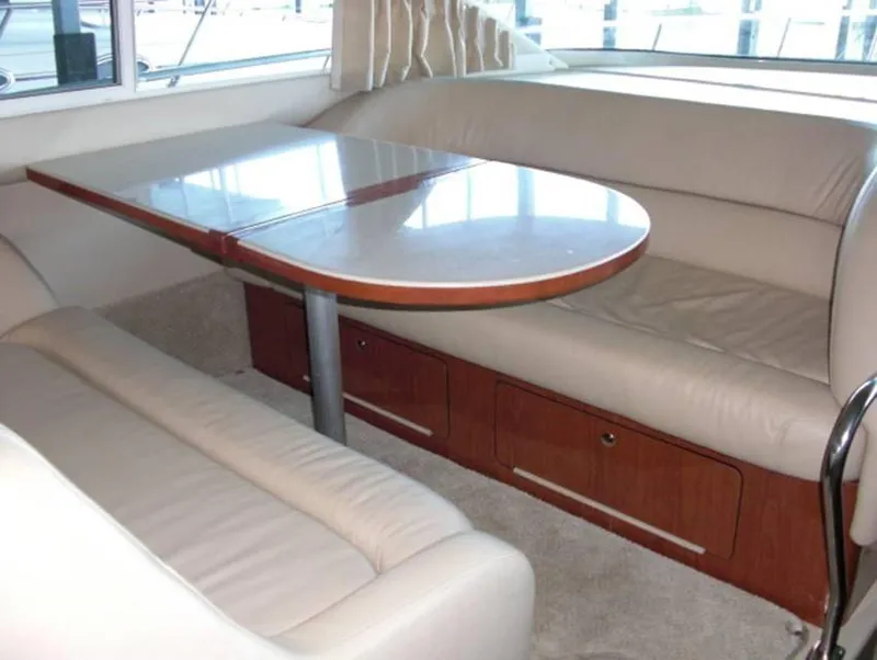 Slide: The Image of 2002 Sea Ray 400 Sedan Bridge interior dining area with leather seating and wooden table. - 8