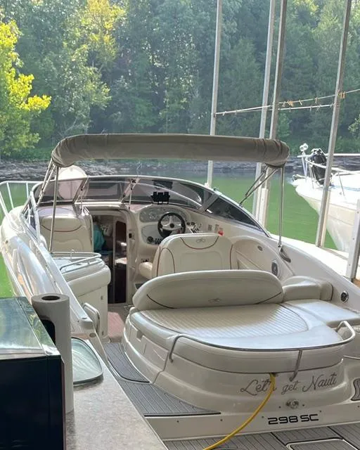 Slide: The Image of 2003 Monterey 298 SC Cruiser docked with canopy and lush green background. - 10