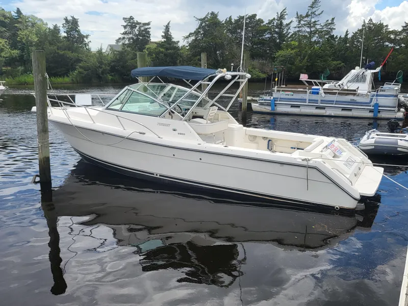 The Image of 2001 Pursuit 2860 Denali boat docked in a marina, surrounded by trees and calm water. - 0
