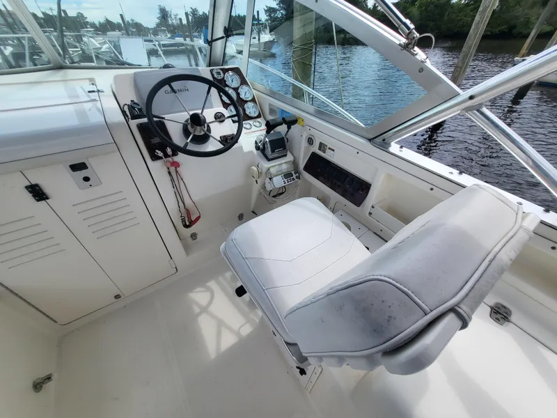 Slide: The Image of 2001 Pursuit 2860 Denali boat cockpit with steering wheel and captain's chair, docked by water. - 1