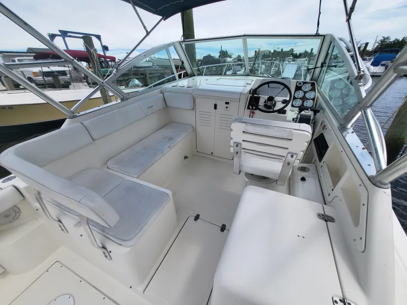 Slide: The Image of 2001 Pursuit 2860 Denali boat interior with helm, seating, and dashboard at a marina. - 10