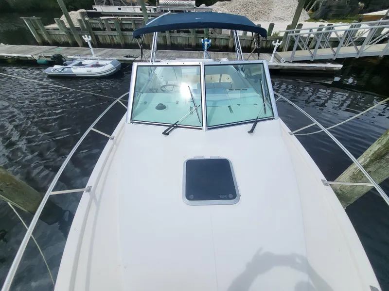 Slide: The Image of 2001 Pursuit 2860 Denali boat docked, featuring a blue canopy and spacious deck. - 19
