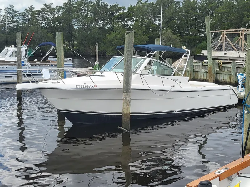 Slide: The Image of 2001 Pursuit 2860 Denali boat docked in a marina, surrounded by calm water. - 2