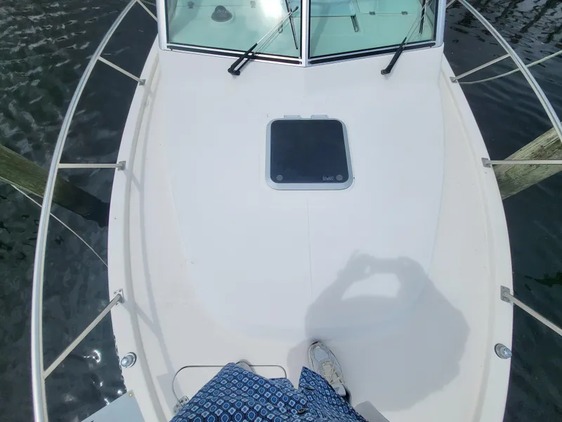 Slide: The Image of 2001 Pursuit 2860 Denali boat deck with windshield and hatch, docked on water. - 21
