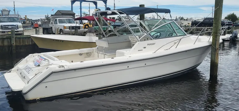 Slide: The Image of 2001 Pursuit 2860 Denali boat docked in marina, featuring sleek white design. - 5