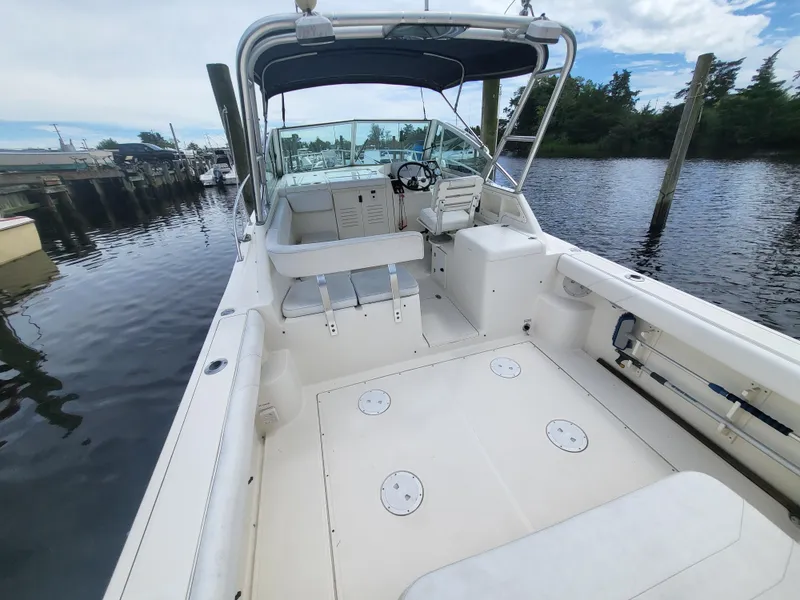 Slide: The Image of 2001 Pursuit 2860 Denali boat docked, featuring spacious deck and helm under a canopy. - 9