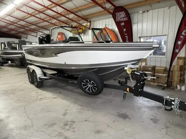 Slide: The Image of 2025 Lund 1975 Tyee boat in showroom, featuring sleek design and modern trailer. - 10