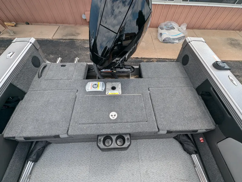 Slide: The Image of Lund 1975 Tyee 2025 boat interior with motor, gray deck, and storage compartments. - 8