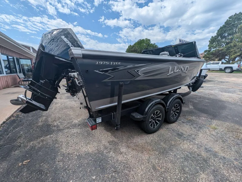 Slide: The Image of 2025 Lund 1975 Tyee boat with Mercury engine on a trailer, parked outdoors. - 10