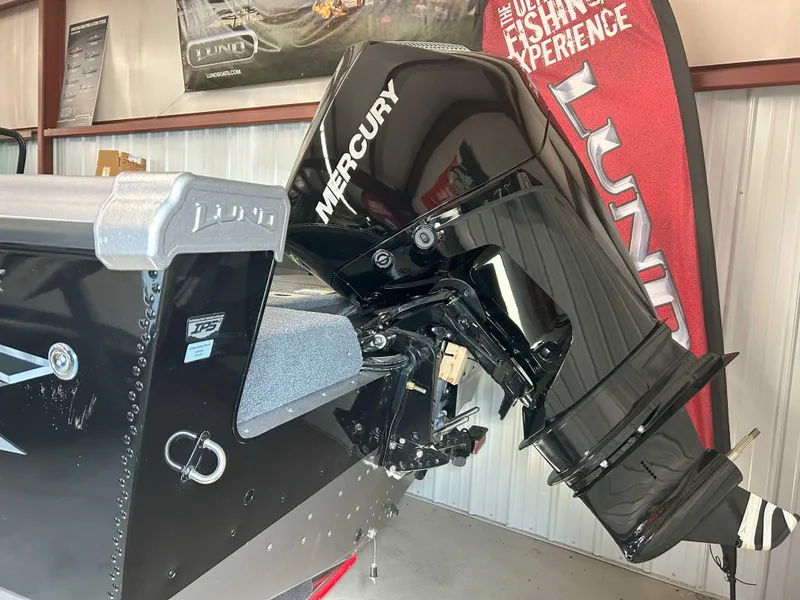 Slide: The Image of 2025 Lund 1975 Tyee boat with Mercury outboard motor in showroom. - 2