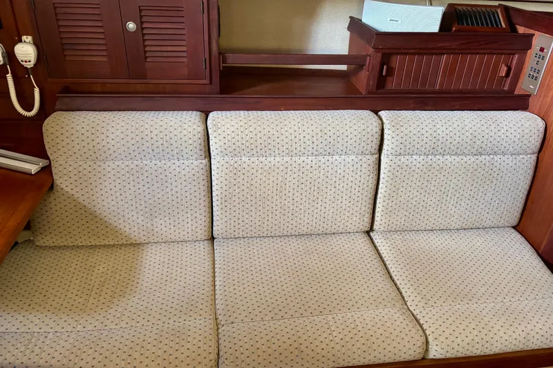 Slide: The Image of Interior of 1999 Island Packet 350 sailboat with cushioned seating and wooden cabinetry. - 13