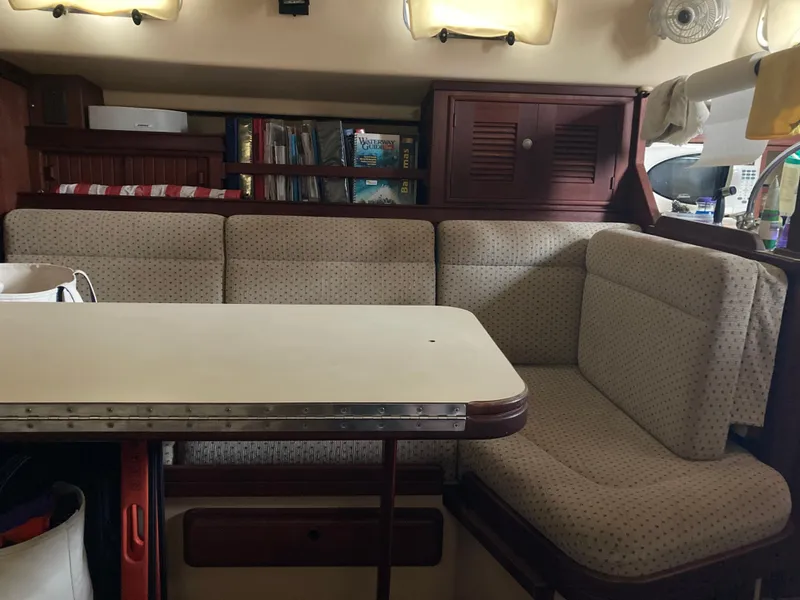 Slide: The Image of Cozy interior of 1999 Island Packet 350 sailboat with cushioned seating and table. - 16