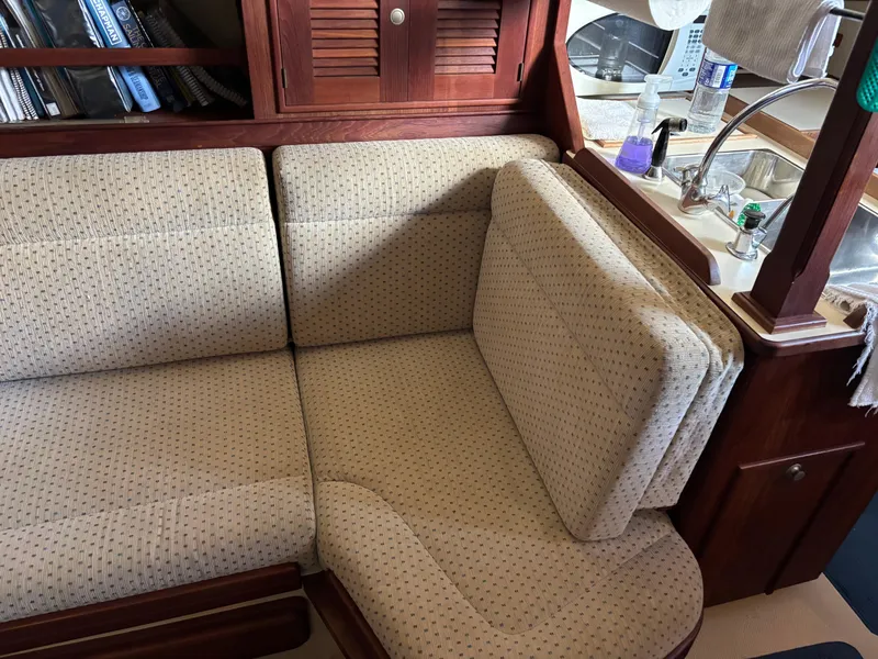 Slide: The Image of Cozy interior of 1999 Island Packet 350 sailboat with cushioned seating and wooden cabinetry. - 17
