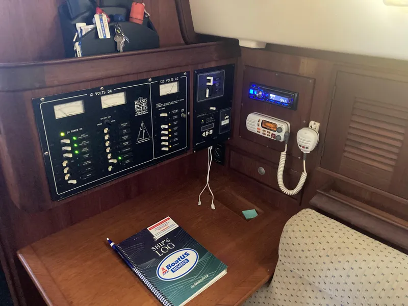 Slide: The Image of Navigation station of a 1999 Island Packet 350 sailboat with control panels and logbook. - 18