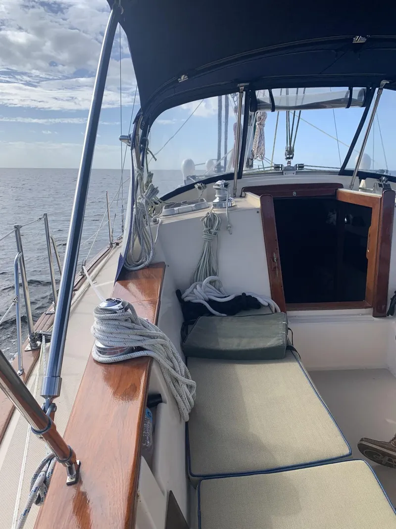 Slide: The Image of 1999 Island Packet 350 sailboat cockpit with cushions, ropes, and ocean view. - 2