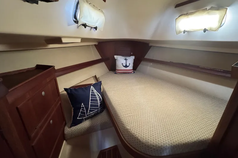 Slide: The Image of 1999 Island Packet 350 sailboat cabin with nautical-themed pillows and wooden cabinetry. - 20