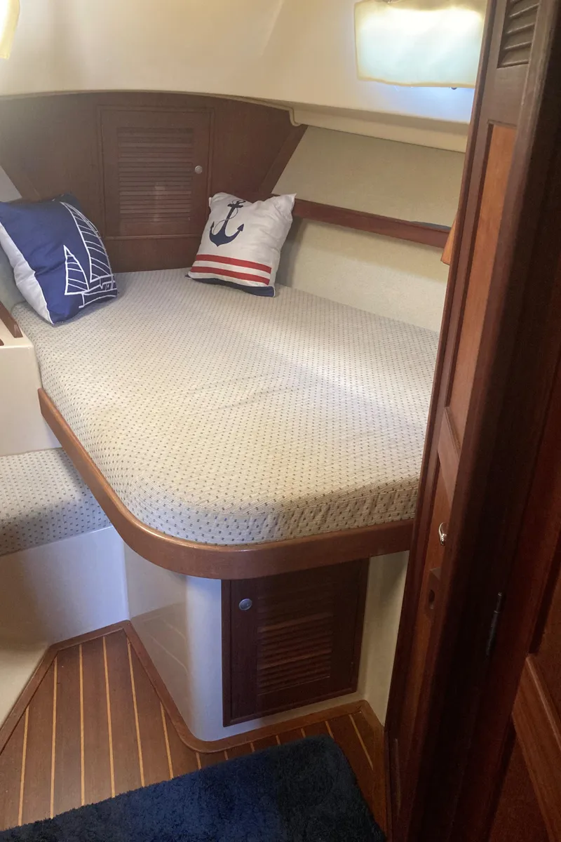 Slide: The Image of 1999 Island Packet 350 sailboat cabin with cozy bed and nautical-themed pillows. - 21
