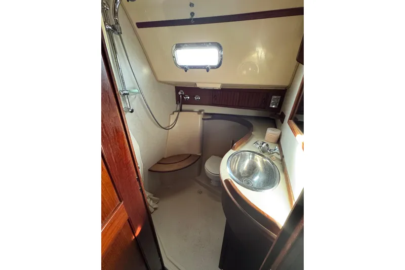 Slide: The Image of 1999 Island Packet 350 yacht bathroom with shower, sink, and wooden accents. - 22