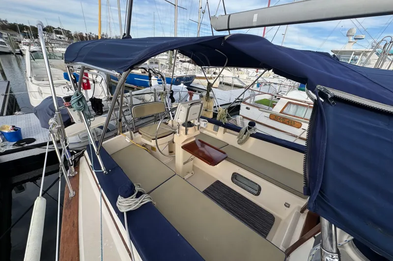 Slide: The Image of 1999 Island Packet 350 sailboat cockpit with blue canopy, docked at marina. - 6